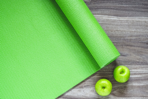 Tapis de yoga vert sur un fond en bois avec des pommes vertes,