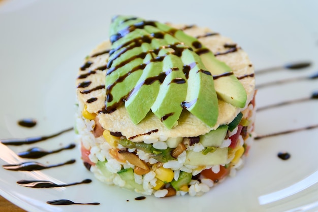 Photo tartare d'avocat avec riz et légumes sur une assiette blanche