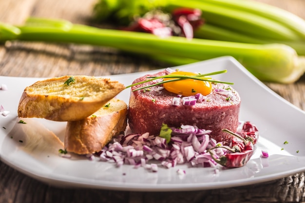 Tartare de boeuf au jaune d'oeuf oignon rouge piments herbes et bruschetta.