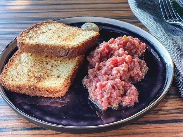 Tartare de boeuf avec du pain croustillant sur une assiette.