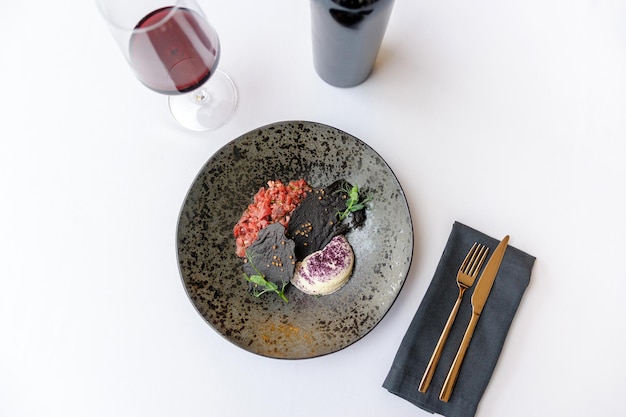 Tartare de boeuf sur une plaque noire avec un verre de vin