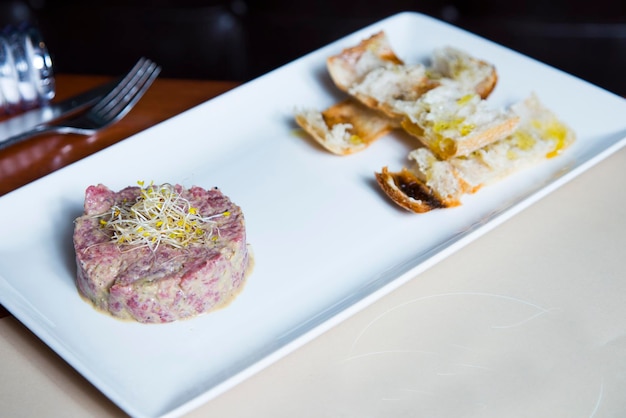 Tartare de steak de boeuf avec oeuf et pain grillé.