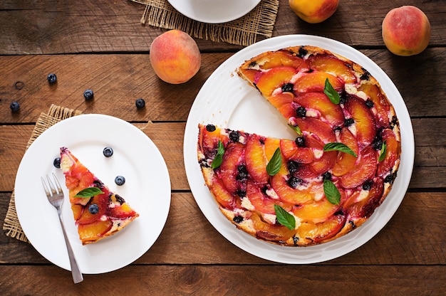 Tarte au biscuit délicat avec des pêches et des bleuets.