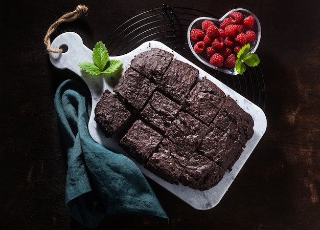 Photo tarte au brownie végétalien au chocolat avec tahini et framboises fraîches sur fond sombre