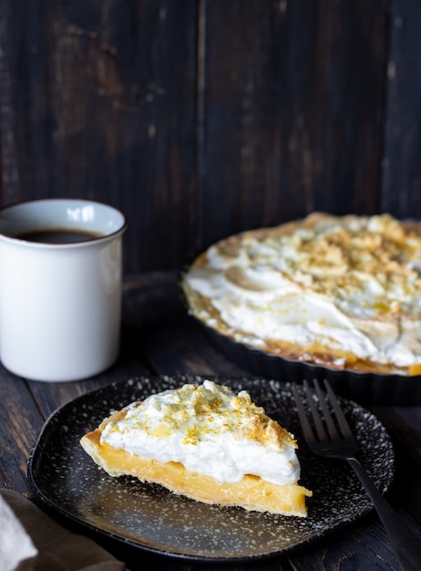 Tarte au citron avec meringue sur un fond en bois.