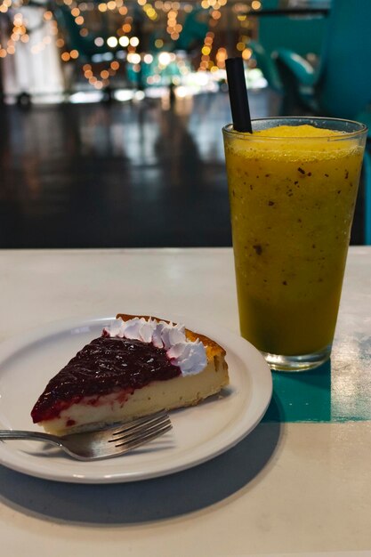 tarte au fromage et aux fruits rouges sur une table en bois accompagnée de jus de mangue