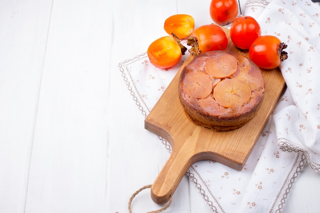 tarte au kaki sur une planche en bois marron sur fond blanc et une nappe blanche