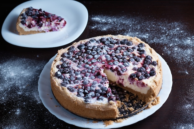 Tarte aux baies préparée sur la table dans la cuisine le cuisinier coupe un morceau d'une surface floue séparée