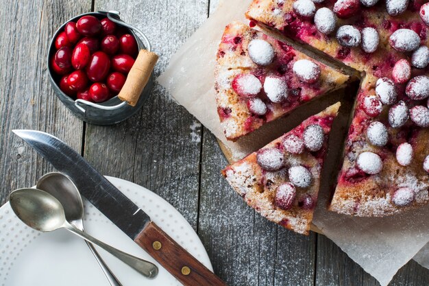 Tarte aux canneberges maison avec des noix, des baies et du sucre en poudre. Vue de dessus. Espace pour le texte. Style rustique. Mise au point sélective.