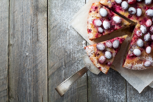 Tarte aux canneberges maison avec des noix, des baies et du sucre en poudre. Vue de dessus. Espace pour le texte. Style rustique. Mise au point sélective.