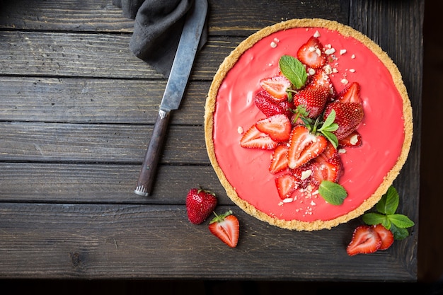 Tarte aux fraises et crème fouettée au mascarpone décorée de fraises fraîches sur bois rustique