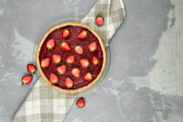 Tarte aux fraises d'été décorée de baies fraîches sur table en béton gris, vue du dessus, espace copie