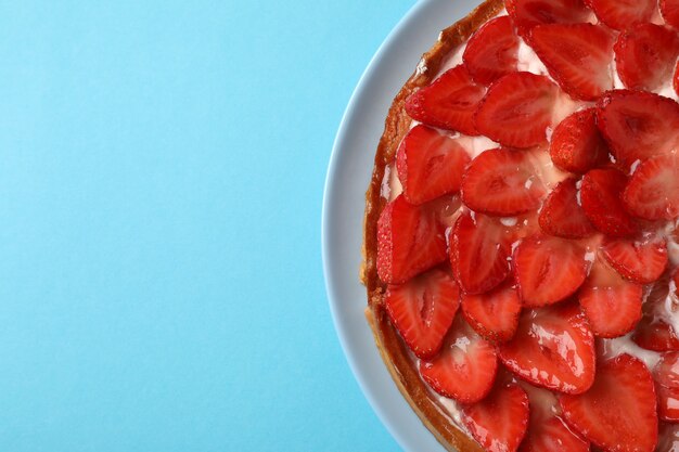 Tarte aux fraises sur fond bleu, espace pour le texte.