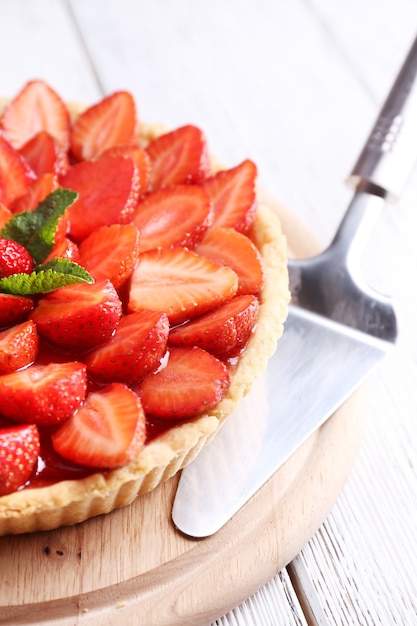 Photo tarte aux fraises sur plateau en bois, sur fond de bois de couleur