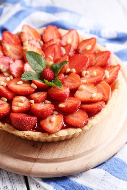 Tarte aux fraises sur plateau en bois, sur fond de bois de couleur