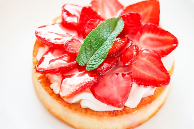 Tarte aux fraises rouge avec gâteau aux feuilles de menthe verte sur fond blanc mise au point sélective