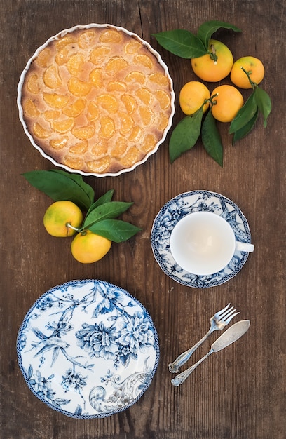 Tarte aux mandarines maison, fruits frais et vaisselle en porcelaine sur bois rustique