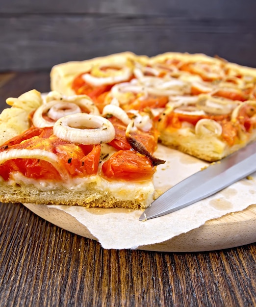 Tarte aux oignons et tomates sur papier avec couteau