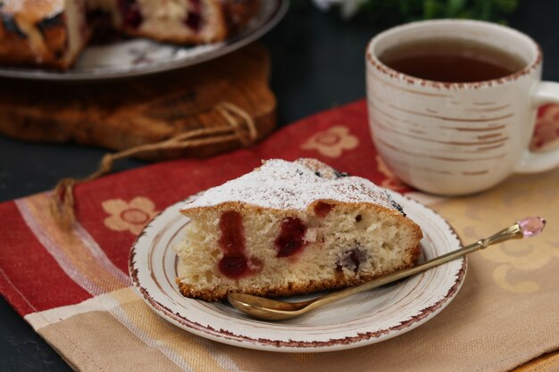 Tarte aux petits fruits avec des cerises est située sur une plaque sur une surface sombre