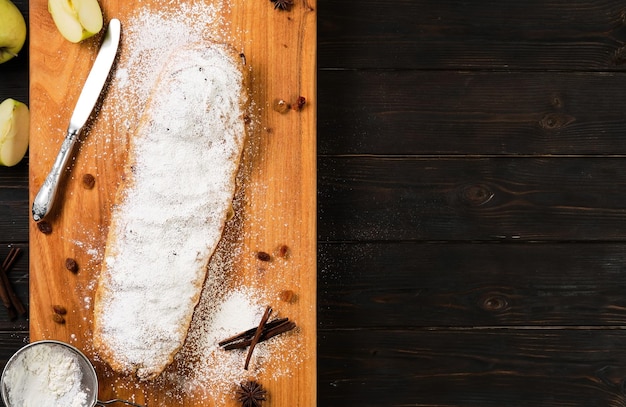 Photo tarte aux pommes - apfelstrudel, un dessert autrichien cuit au four avec des pommes caramélisées, des noix, de la cannelle, des raisins secs, sur une planche à découper en bois avec des bâtons d'anis et de cannelle. vue de dessus avec espace de copie