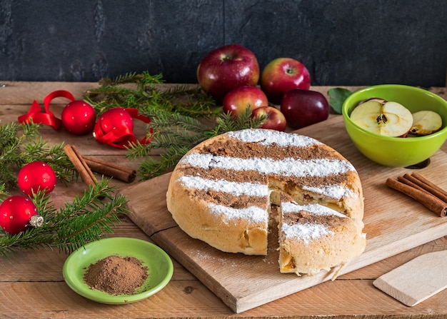 Tarte aux pommes à la cannelle maison ronde avec des décorations de Noël et des ingrédients pour cuisiner autour