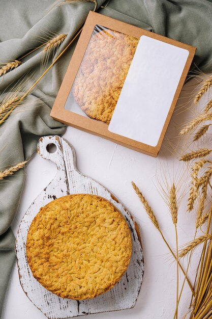 Photo une tarte aux pommes faite maison sur une planche à couper rustique avec un décor de blé