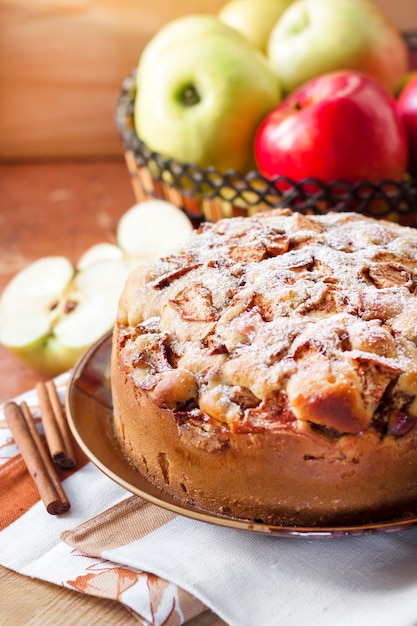 Tarte aux pommes maison avec de la cannelle sur l'assiette et des pommes vertes et rouges dans le