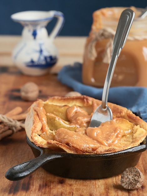 Tarte aux pommes maison avec sauce au caramel sur une table en bois. Fermer. Près d'un pot de caramel, de lait et d'épices. Délicieux dessert.