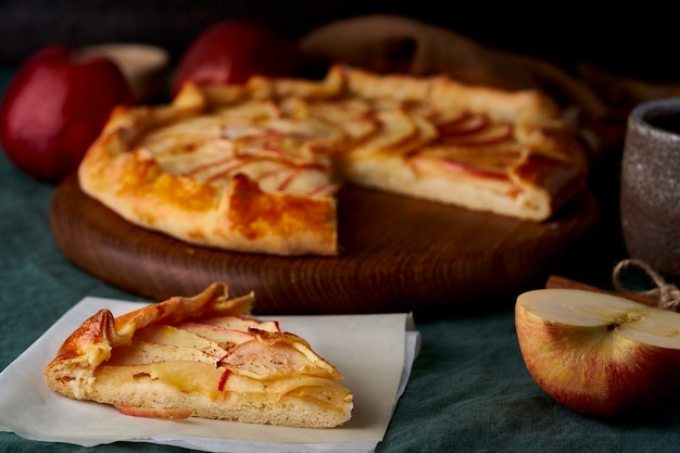 Tarte aux pommes avec morceau de tranche de galette aux fruits, tranches de pâtisseries sucrées sur nappe vert foncé