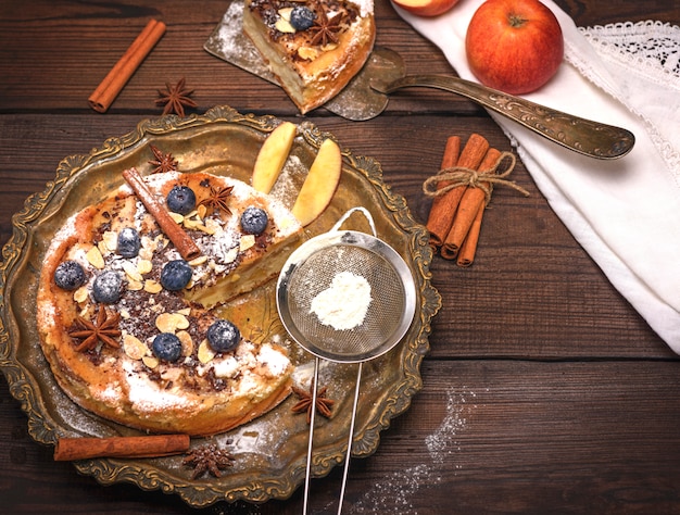 Tarte aux pommes ronde au four et tamis en fer avec sucre en poudre