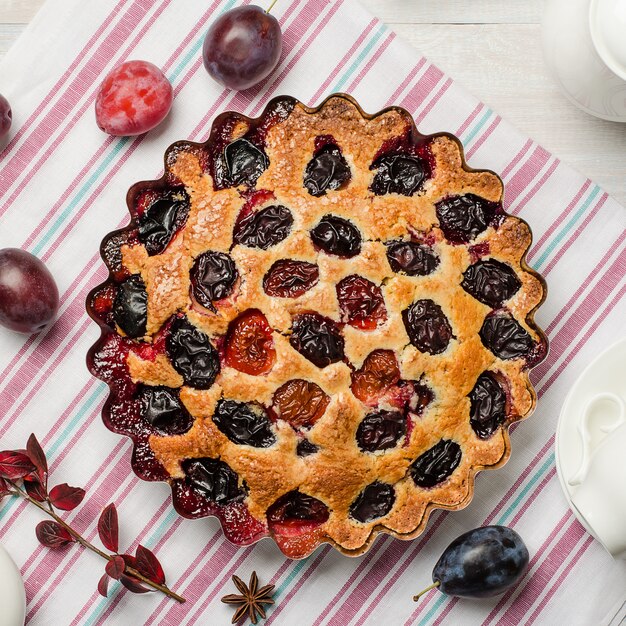 Tarte aux prunes sur un fond en bois clair. Cuisson maison