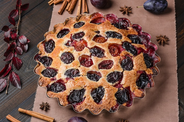 Tarte aux prunes sur un fond en bois sombre. Cuisson maison