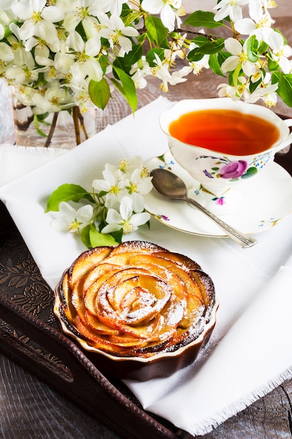 Tarte aux roses en forme de pomme et tasse de thé sur le plateau de service