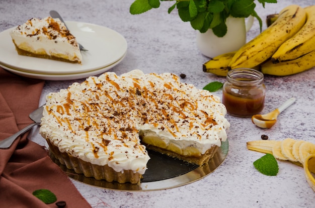 Tarte Banoffee traditionnelle avec bananes fraîches, crème fouettée, chocolat, café et caramel. Pas de dessert au four. Orientation horizontale.