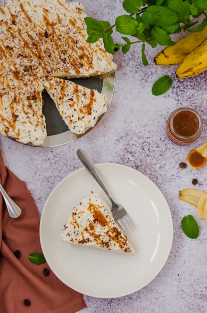 Tarte Banoffee traditionnelle avec bananes fraîches, crème fouettée, chocolat, café et caramel. Pas de dessert au four. Orientation verticale. Vue de dessus.