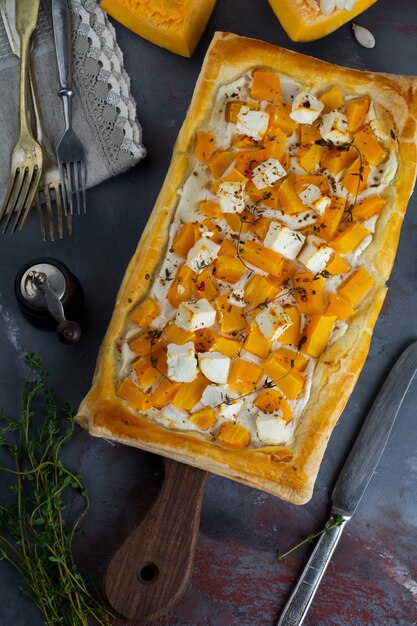 Tarte à la citrouille, feta, ricotta et thym sur une surface de béton sombre