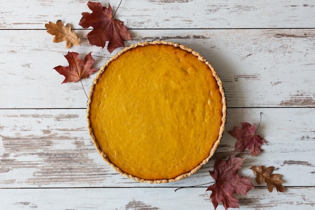 Tarte à la citrouille maison fraîche dans un plat allant au four sur la vue de dessus de table en bois blanc