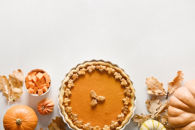 Tarte à la citrouille savoureuse maison avec des décorations d'automne et des feuilles pour le jour de Thanksgiving sur blanc