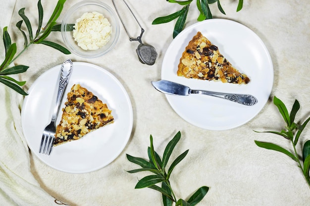 Tarte à la crème maison avec flocons d'amandes et plantes de ruscus sur fond grunge