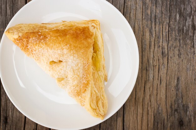 Tarte croustillante sur une plaque blanche sur une table en bois.