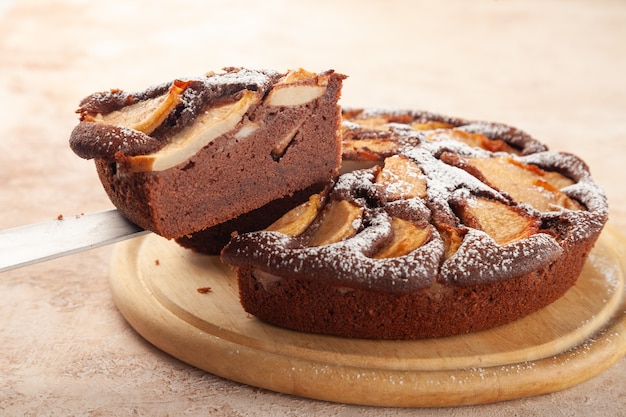 Tarte maison au chocolat, pommes, morceau de gâteau coupé sur le couteau, plaque en bois, espace copie, place pour le texte, vue de côté, gros plan