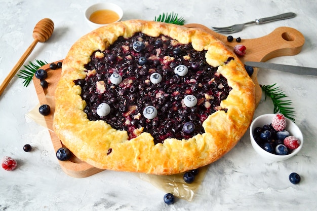 Photo tarte ouverte ou galette avec des baies, des couverts et des baies fraîches sur une table concept alimentaire sain. nourriture rustique.