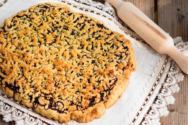 Tarte râpée appétissante avec de la confiture sur une serviette Gros plan d'une tarte au four avec une croûte dorée Lampe de table en bois depuis la fenêtre