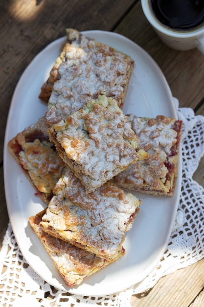 Tarte Streusel farcie à la confiture de rose, servie avec café. Style rustique.