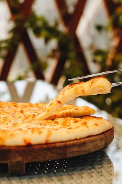 Tarte en tranches avec du fromage sur une planche de bois sur fond gris. Khachapuri