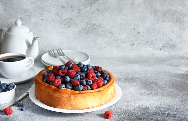 Tarte à la vanille aux bleuets framboises sur la table de la cuisine avec une tasse de café Cheesecake avec b