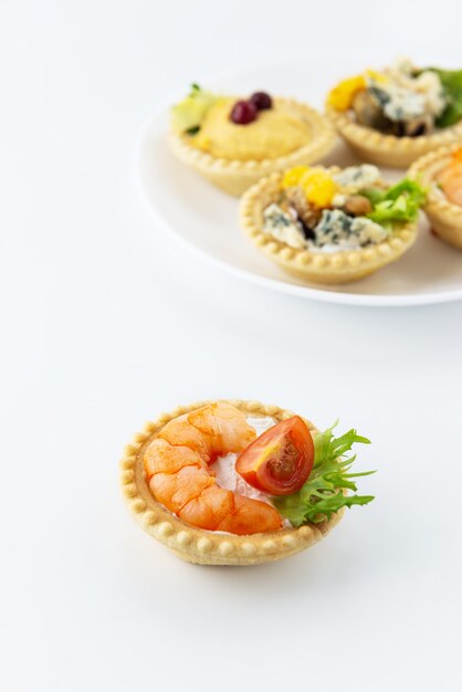 Tartelette aux crevettes, tomates et herbes sur le fond d'une assiette avec tartelettes