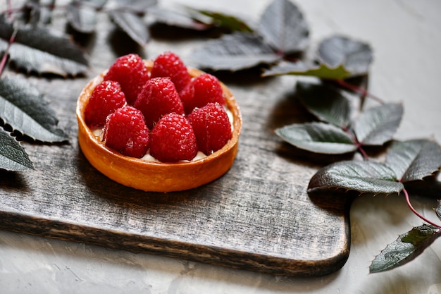 Tartelette aux framboises. Dessert sur le tableau noir. Décoration de dessert avec des dépliants.