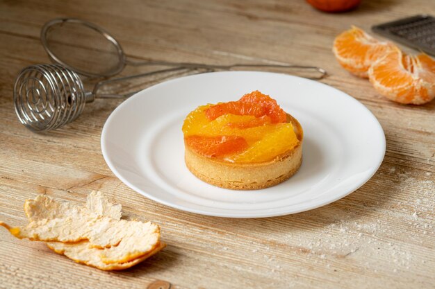 Tartelette à la mandarine et au pamplemousse se trouve sur une assiette sur une table en bois beau dessert