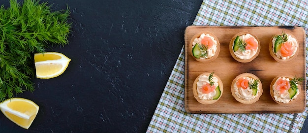 Tartelettes au fromage à la crème et saumon salé. Collation légère et savoureuse pour une fête. Nourriture à manger avec les doigts. La vue de dessus. Bannière